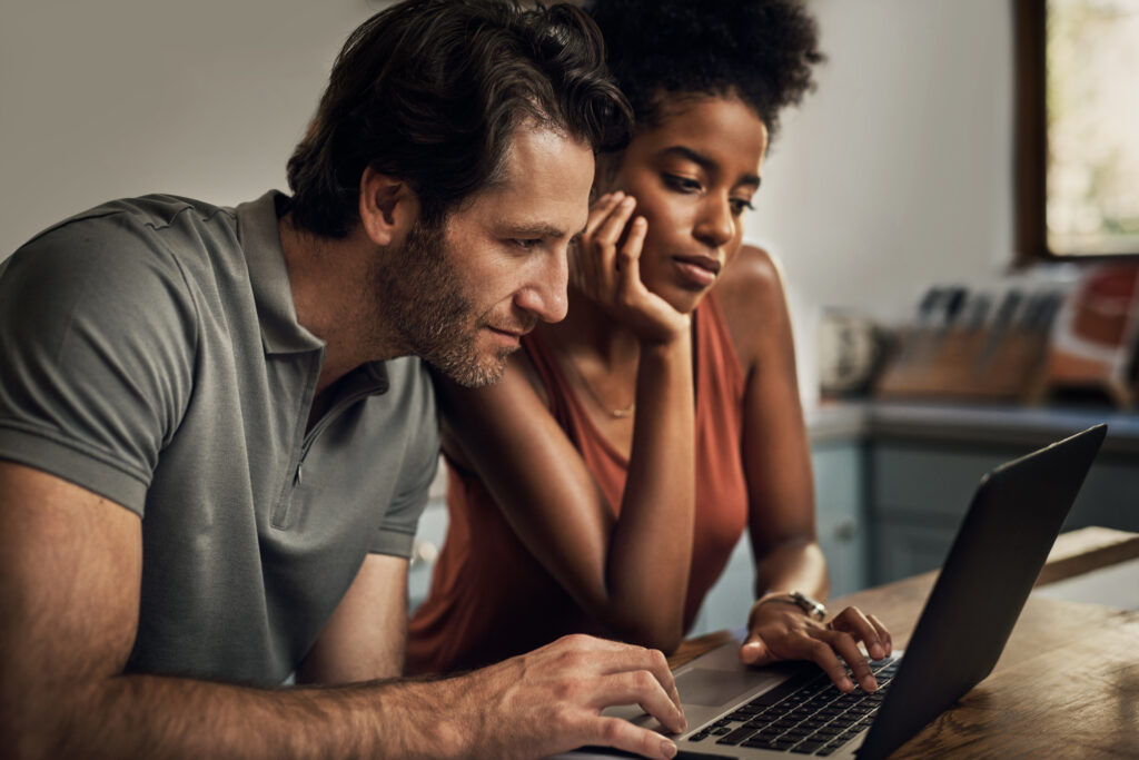 Couple looks at computer paying bills with pre-settlement funding awaiting a settlement decision
