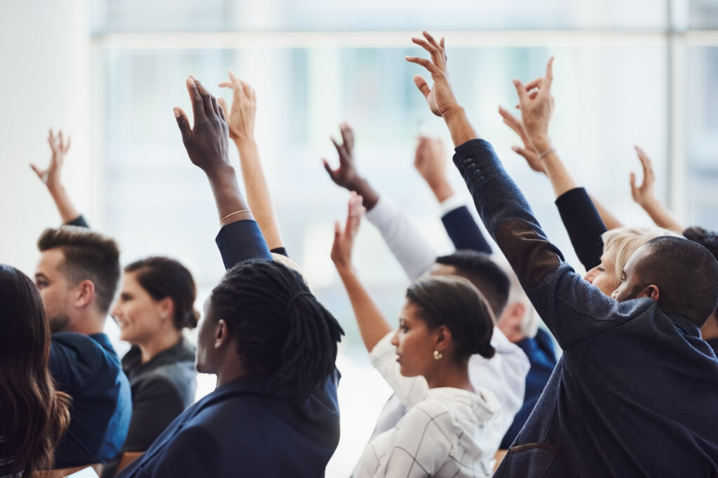 A group of people raising their hands to ask questions