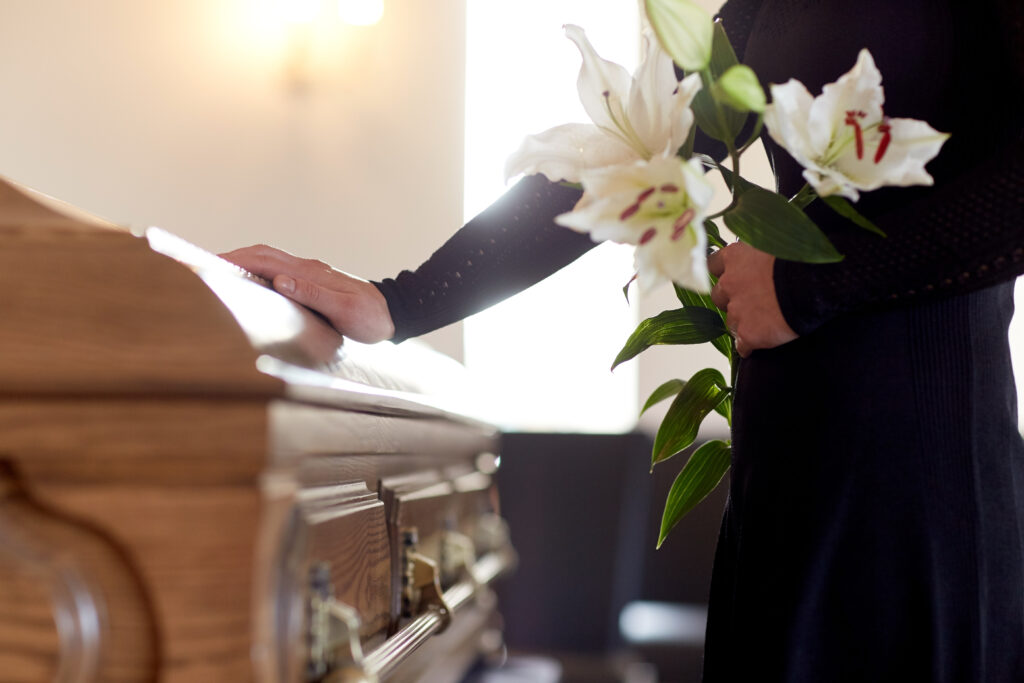 Spouse mourns at a funeral holding flowers