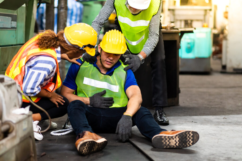 Industrial workers gathered around a colleague who had a slip and fall at work