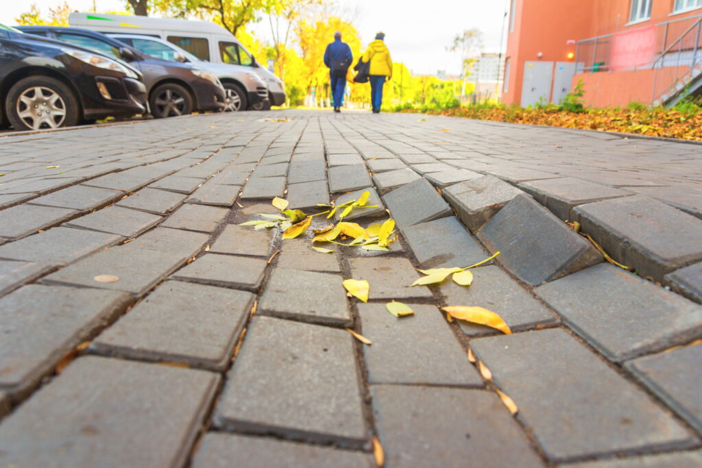 Defective sidewalk with people walking in the background