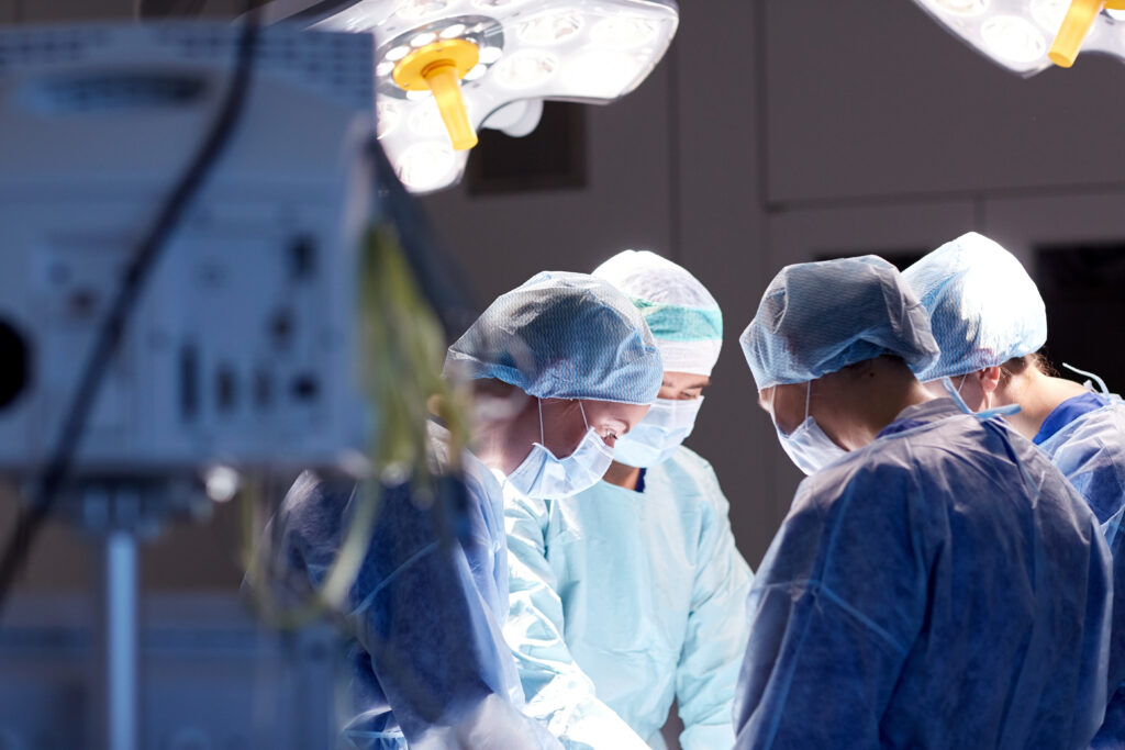 Surgeons gather around a patient to perform a surgery